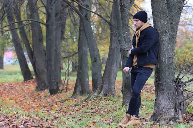 Uomo bello barba nel parco autunnale in posa sulla macchina fotografica