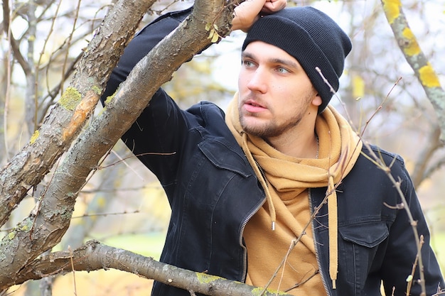 Uomo bello barba nel parco autunnale in posa sulla macchina fotografica