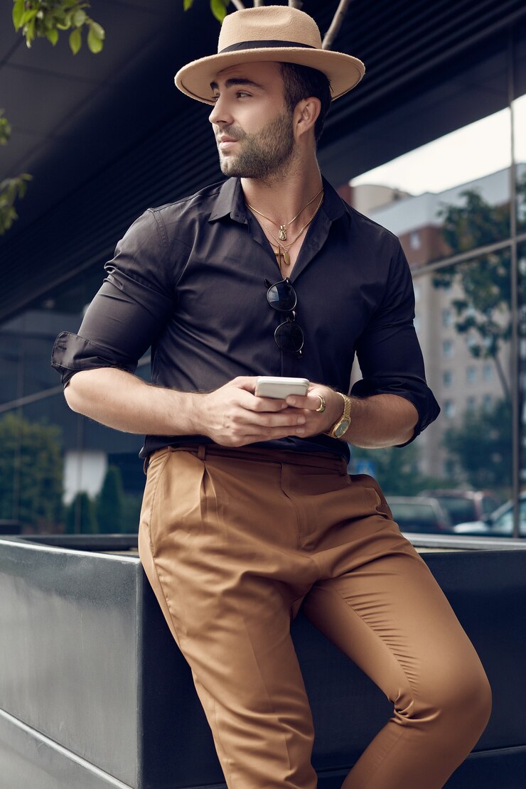 Foto uomo bello brutale abbronzato muscoloso hipster in camicia e cappello neri con il telefono