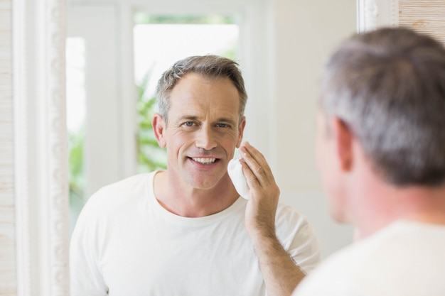 Uomo bello che applica schiuma da barba nel bagno