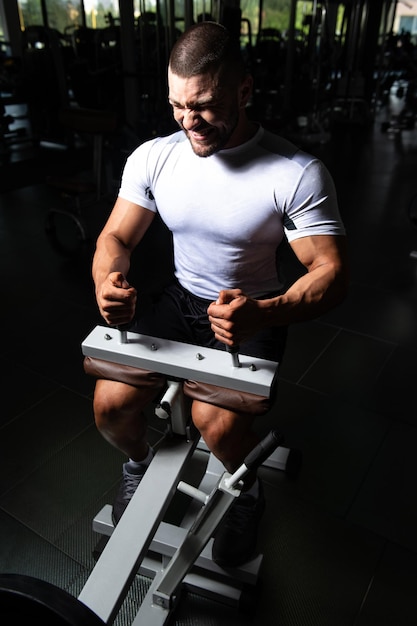 Uomo bello che esercita i polpacci nel centro fitness