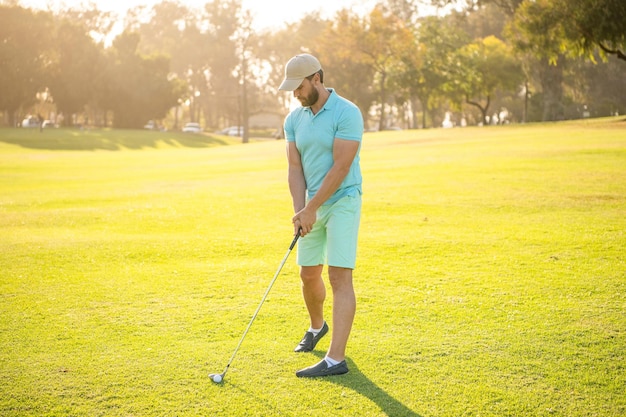 Uomo bello che gioca a golf sulla ricreazione di erba verde