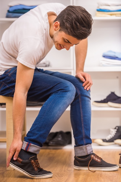 Uomo bello che indossa le scarpe mentre sedendosi sulla sedia.