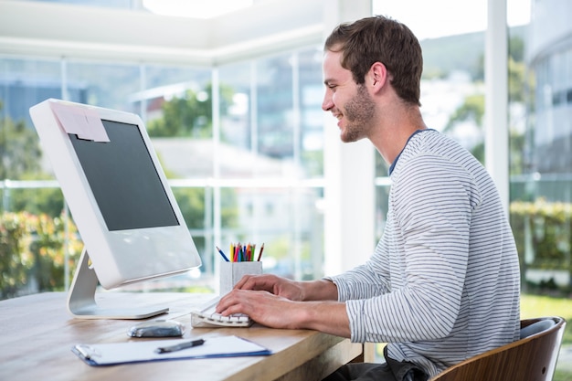 Uomo bello che lavora al computer in un ufficio luminoso