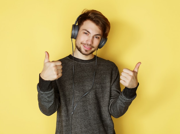 Uomo bello che lictening alla musica sopra fondo giallo