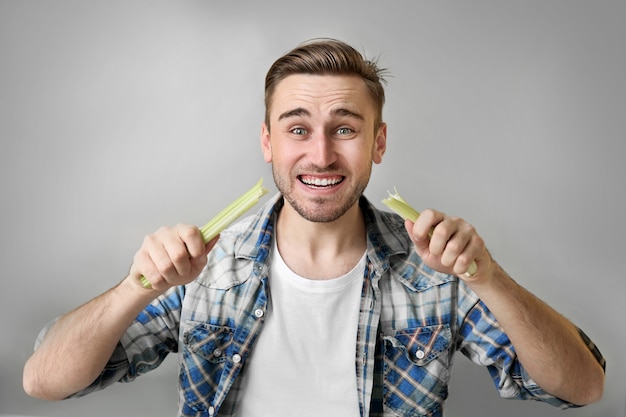 Uomo bello che mangia il sedano