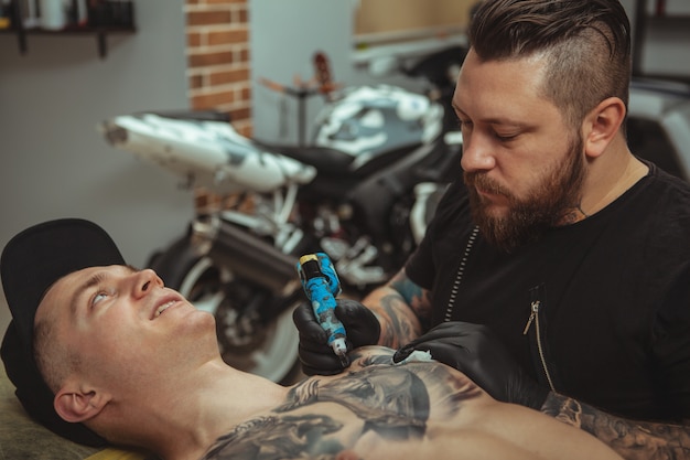 Uomo bello che ottiene un tatuaggio allo studio di arte alternativa