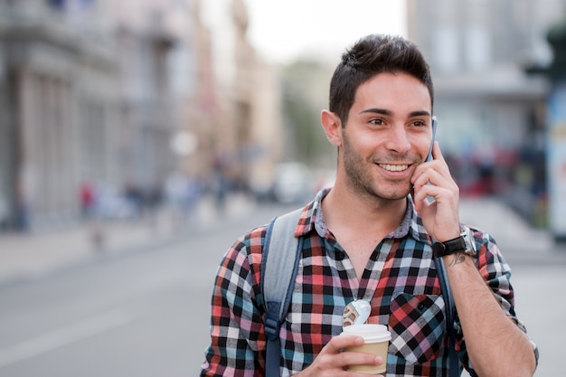 Uomo bello che parla al telefono nelle strade della città