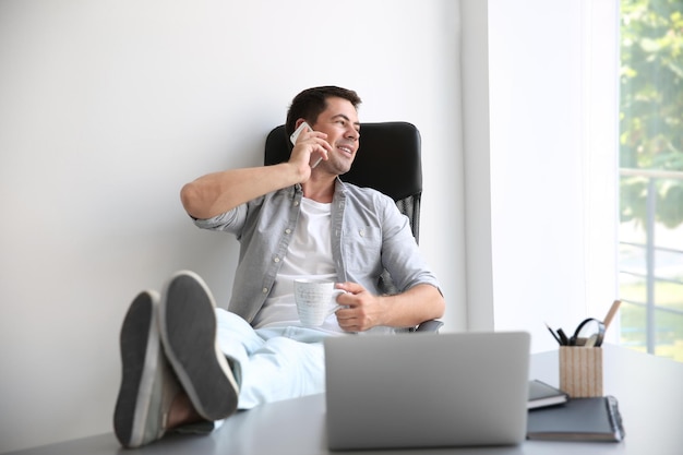 Uomo bello che parla sul telefono cellulare e che beve caffè