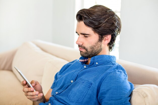 Uomo bello che per mezzo del telefono cellulare a casa