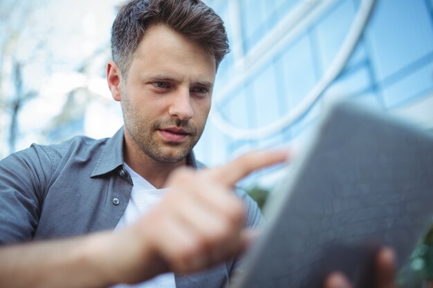 Uomo bello che per mezzo della compressa digitale