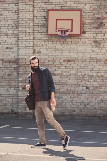 Uomo bello che posa sul cortile di pallacanestro