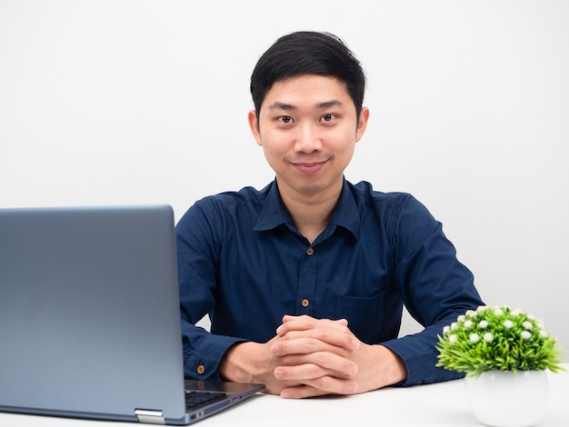 Uomo bello che sembra sicuro di sé seduto al tavolo con il computer portatile sul posto di lavoro