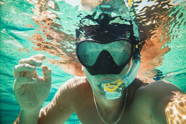 Uomo bello che si diverte in vacanza e fa un selfie subacqueo durante le immersioni subacquee in mare.