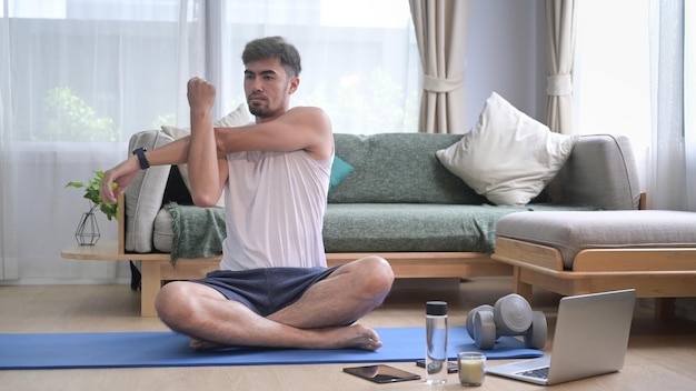 Uomo bello che si riscalda allungando le braccia prima dell'allenamento a casa