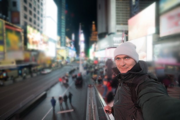 Uomo bello che sorride e che prende la foto del selfie su Times Square a New York