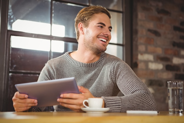 Uomo bello che sorride e che tiene computer tablet