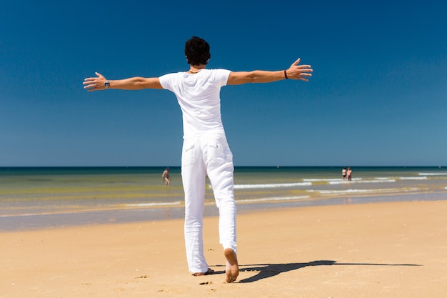 Uomo bello che sta al sole sulla spiaggia