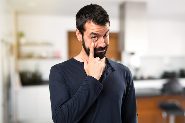 Uomo bello con barba che mostra qualcosa all&#39;interno della casa