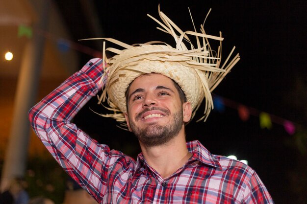 Uomo bello con i vestiti tipici della festa junina che sorride alla festa junina