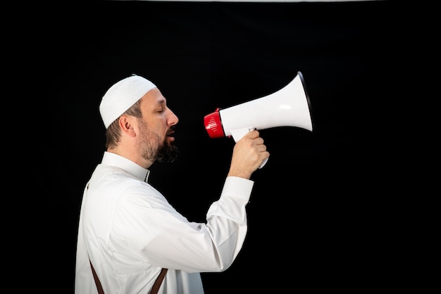 Uomo bello con la barba che grida attraverso il megafono per hajj in mekkah