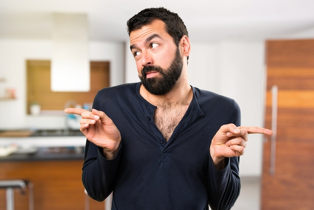 Uomo bello con la barba che punta ai laterali che hanno dubbi all&#39;interno della casa