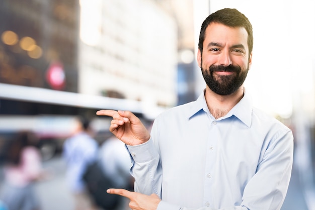 Uomo bello con la barba che punta alla laterale su sfondo unfocused