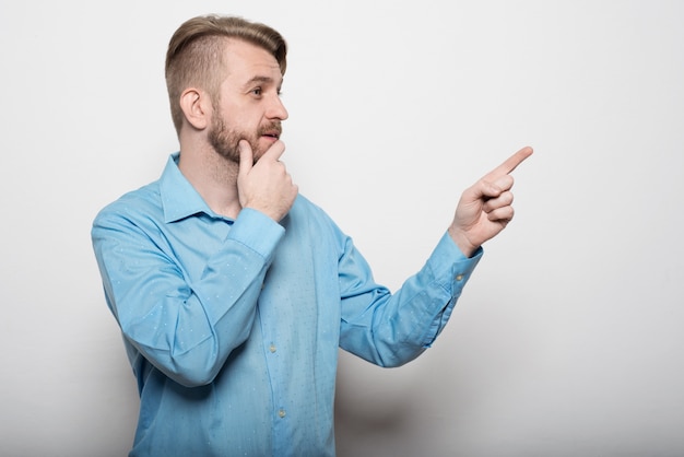 Uomo bello con la barba che punta in una direzione su bianco