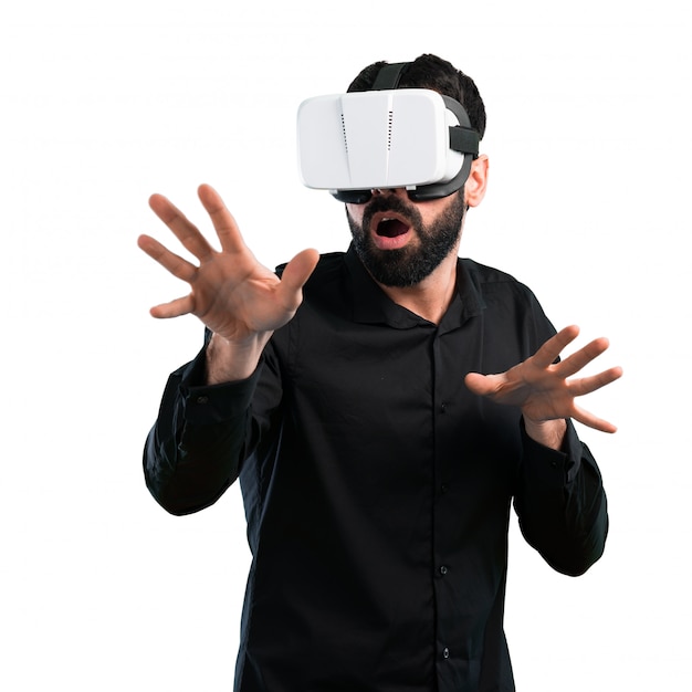 Uomo bello con la barba che usando i vetri di VR su fondo bianco