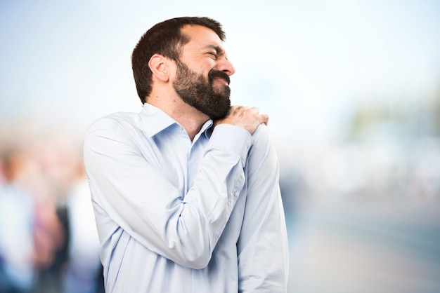 Uomo bello con la barba con dolore alla spalla su sfondo unfocused