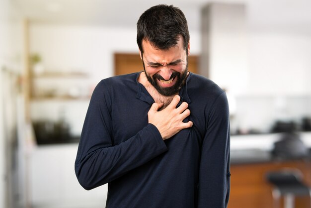 Uomo bello con la barba con dolore cardiaco all&#39;interno della casa