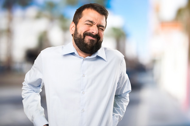 Uomo bello con la barba con il mal di schiena su sfondo unfocused