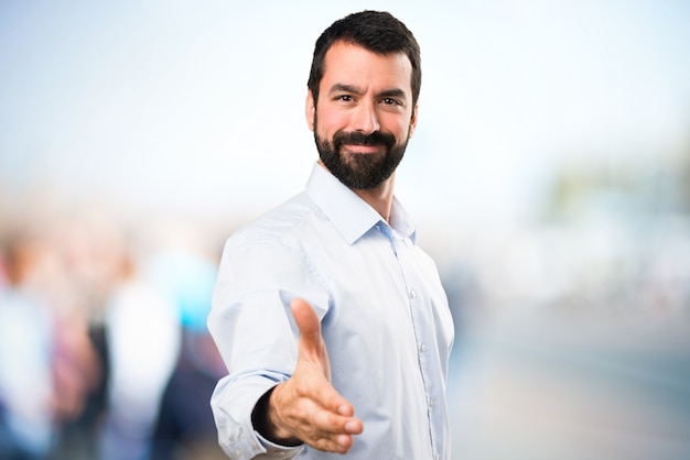 Uomo bello con la barba fare un affare su sfondo unfocused