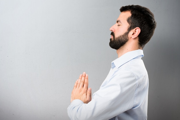 Uomo bello con la barba in posizione zen su sfondo testurizzato