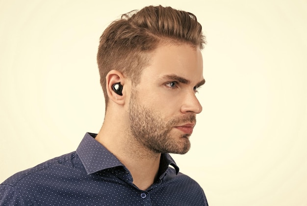 Uomo bello con la barba lunga con auricolari bluetooth wireless isolati su tecnologia bluetooth bianca