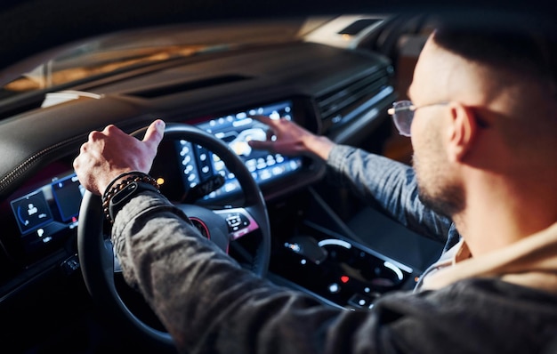 Uomo bello con la barba lunga in abiti alla moda che guida la sua automobile