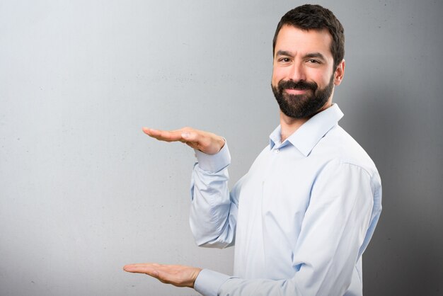 Uomo bello con la barba tenendo qualcosa su sfondo testurizzato