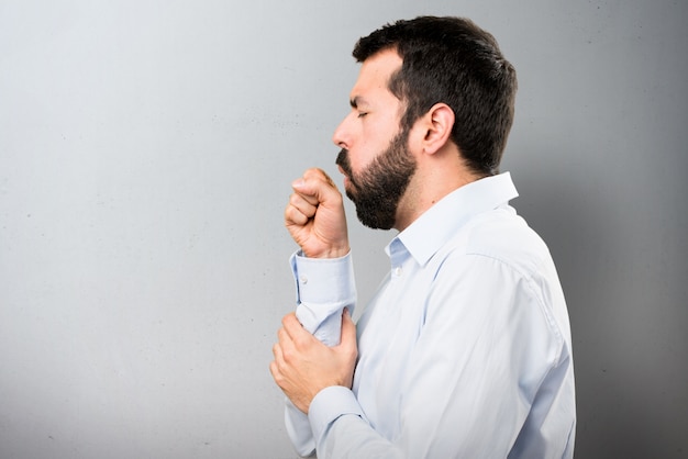 Uomo bello con la barba tosse molto su sfondo testurizzato