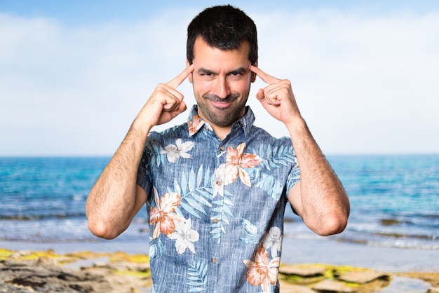 Uomo bello con la camicia di fiori che pensa alla spiaggia