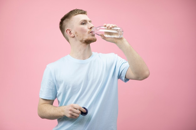 Uomo bello del corpo in forma in maglietta che beve acqua dolce dalla bottiglia