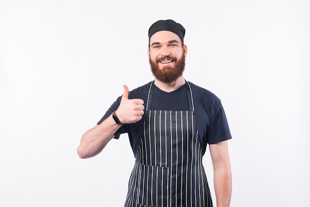 Uomo bello del cuoco unico con la barba che mostra pollice sul gesto