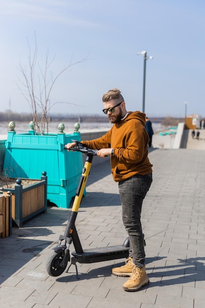 Uomo bello del ragazzo che guida il concetto di tecnologia di trasporto eco di scooter moderno urbano elettrico