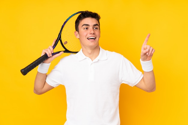 Uomo bello del tennis dell'adolescente isolato su giallo