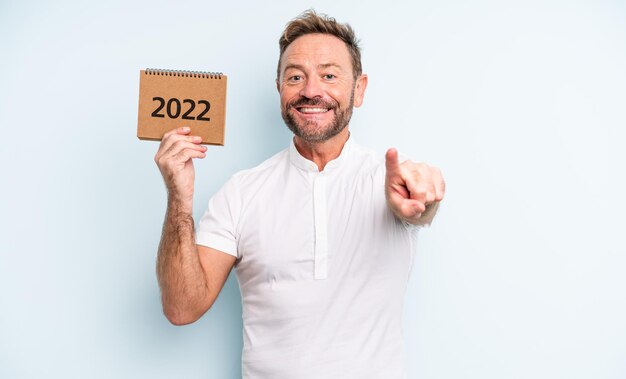 Uomo bello di mezza età che punta alla telecamera scegliendo te. concetto di calendario 2022