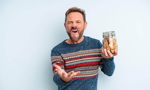 Uomo bello di mezza età che sembra arrabbiato, infastidito e frustrato. bottiglia di biscotti