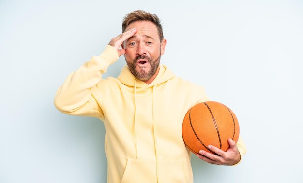 Uomo bello di mezza età che sembra felice, stupito e sorpreso. concetto di basket