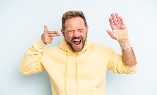 Uomo bello di mezza età che sembra infelice e stressato, gesto suicida che fa il segno della pistola. concetto di mano rotta