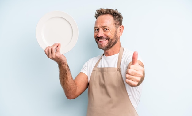 Uomo bello di mezza età che si sente orgoglioso, sorride positivamente con i pollici in su. concetto di piatto vuoto