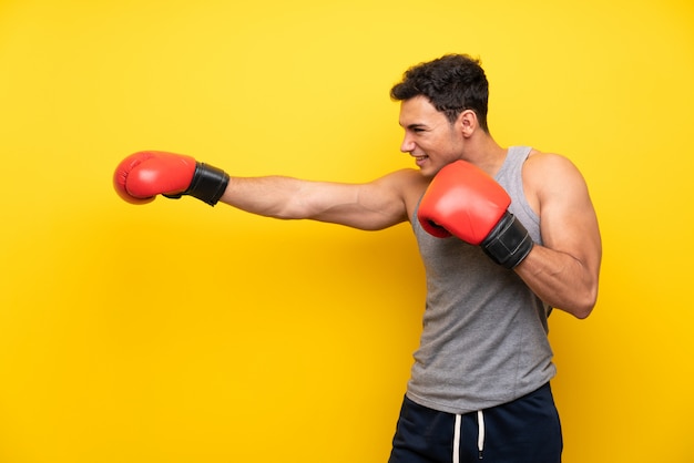 Uomo bello di sport sopra la parete isolata con i guantoni da pugile