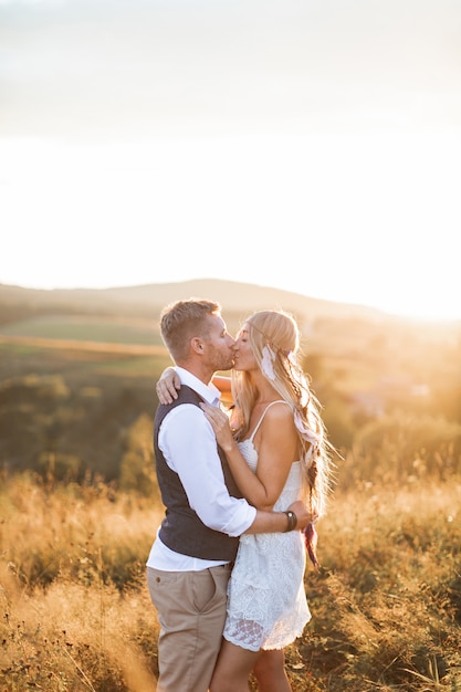 Uomo bello e bella donna in abiti rustici boho elegante, baciare